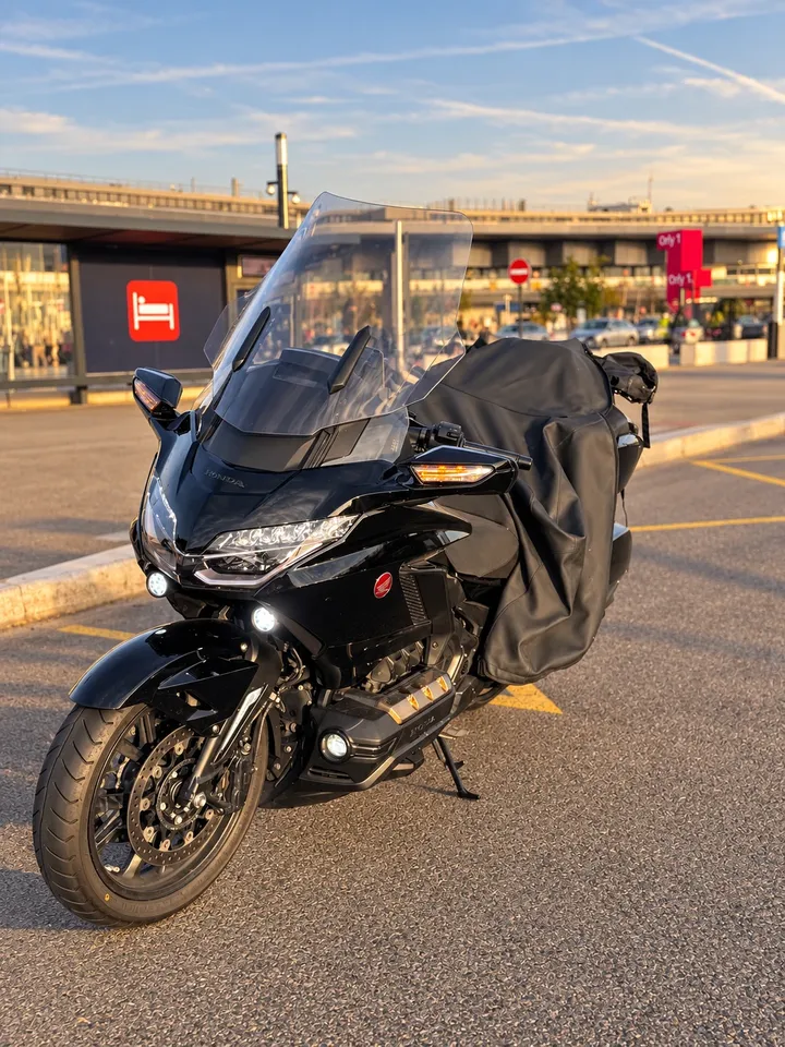 La Honda Gold Wing noire, phares allumés, devant le terminal Orly 1 au coucher du soleil