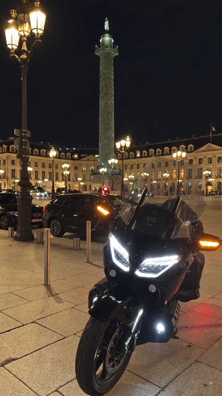 La Gold Wing phares allumés place Vendôme, de nuit, devant la colonne